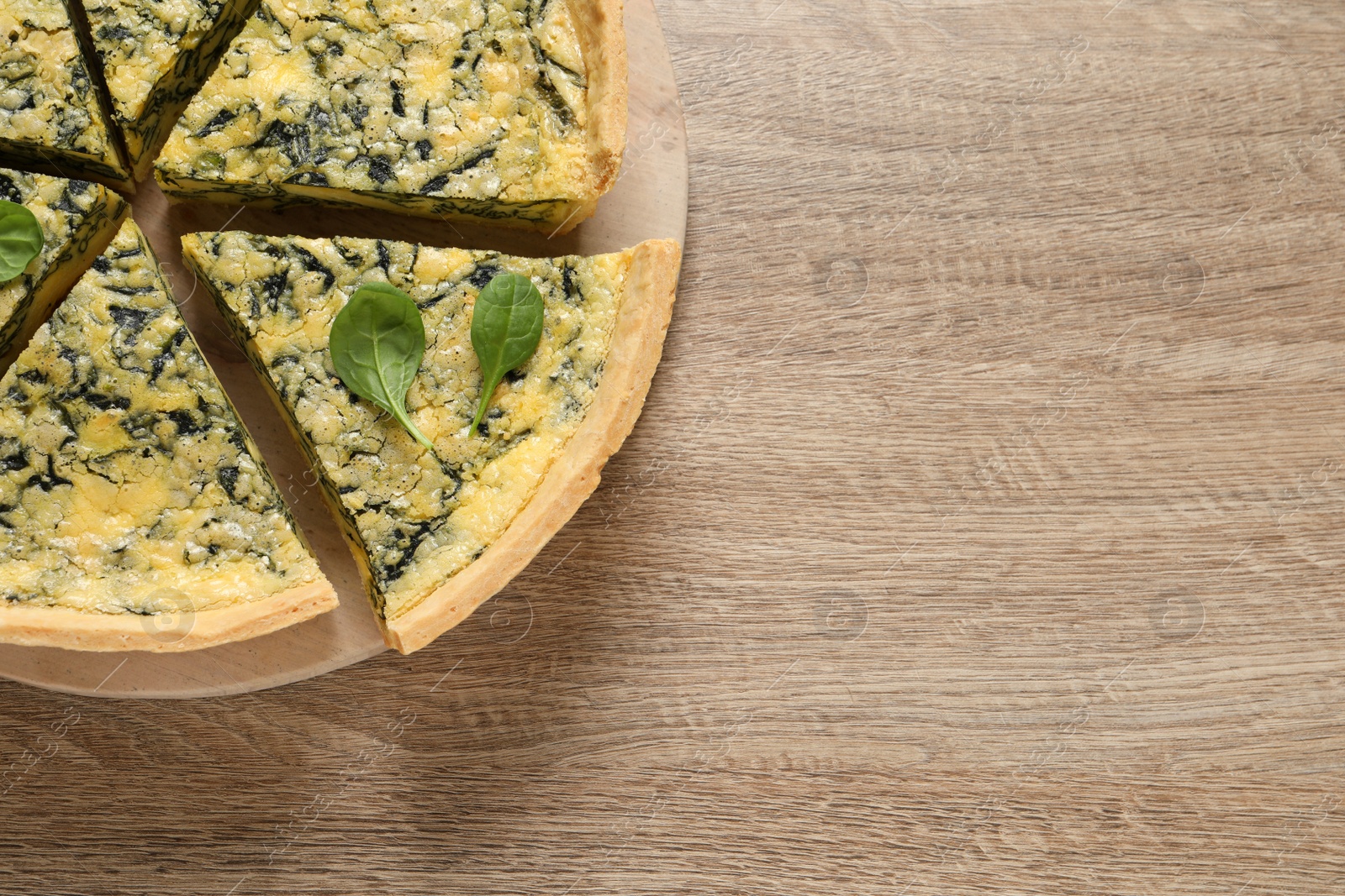 Photo of Cut delicious spinach pie on wooden table, top view. Space for text