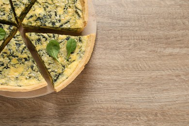 Cut delicious spinach pie on wooden table, top view. Space for text