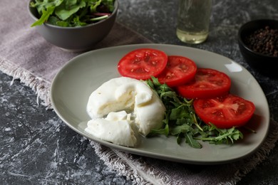 Photo of Delicious burrata cheese with tomatoes and arugula on grey table, closeup