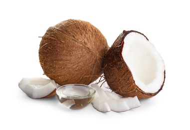 Photo of Ripe coconuts and bowl with natural organic oil on white background