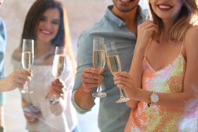 Photo of Friends clinking glasses with champagne at party indoors