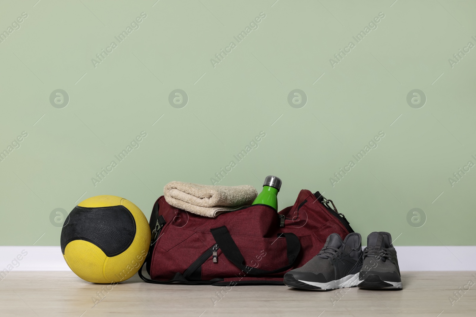 Photo of Gym bag and sports equipment on floor indoors