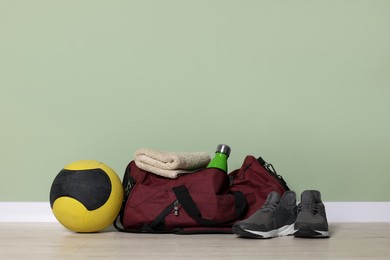 Photo of Gym bag and sports equipment on floor indoors