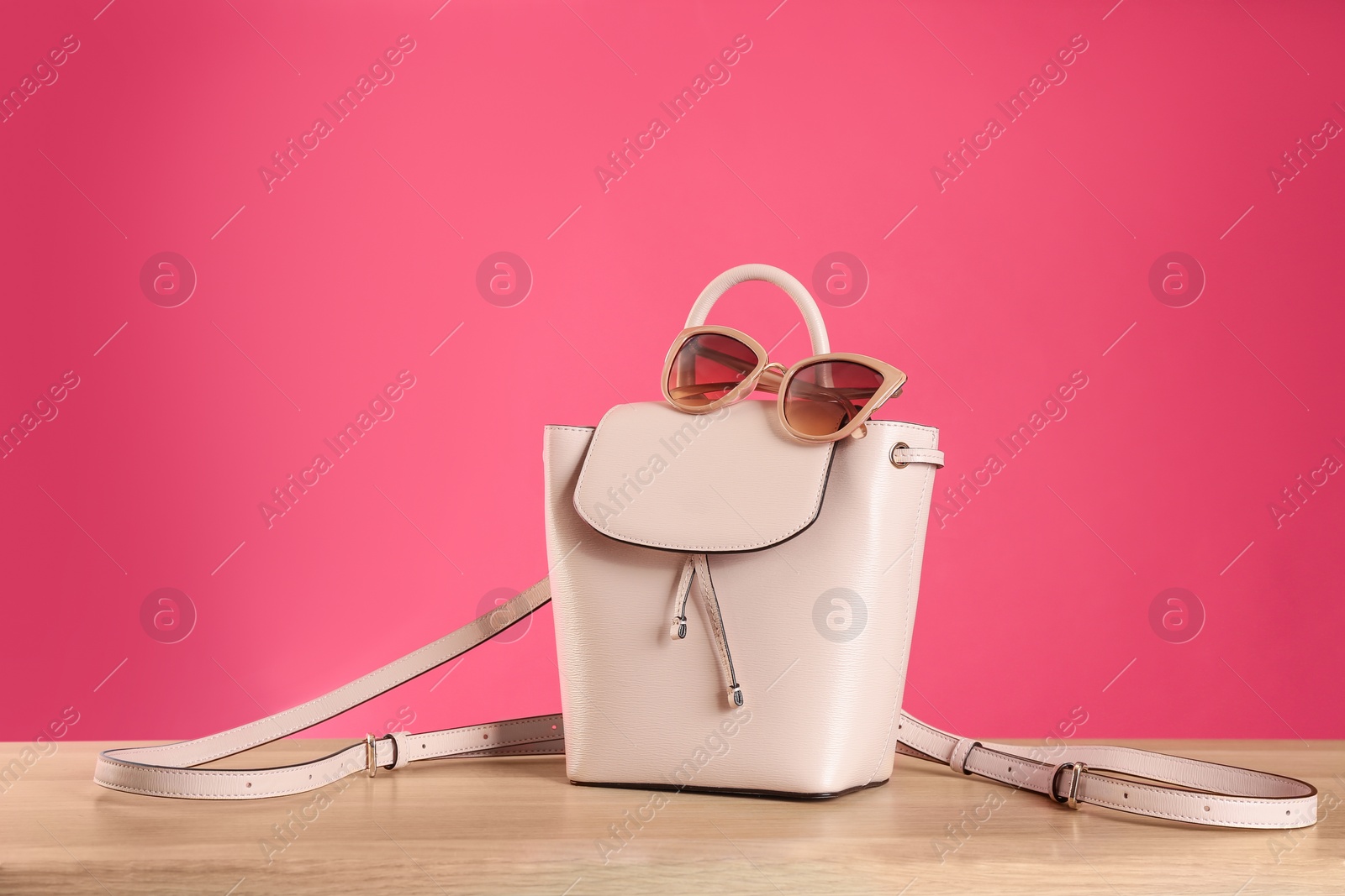 Photo of Stylish woman's bag and sunglasses on wooden table