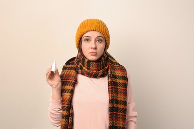 Woman with nasal spray on beige background