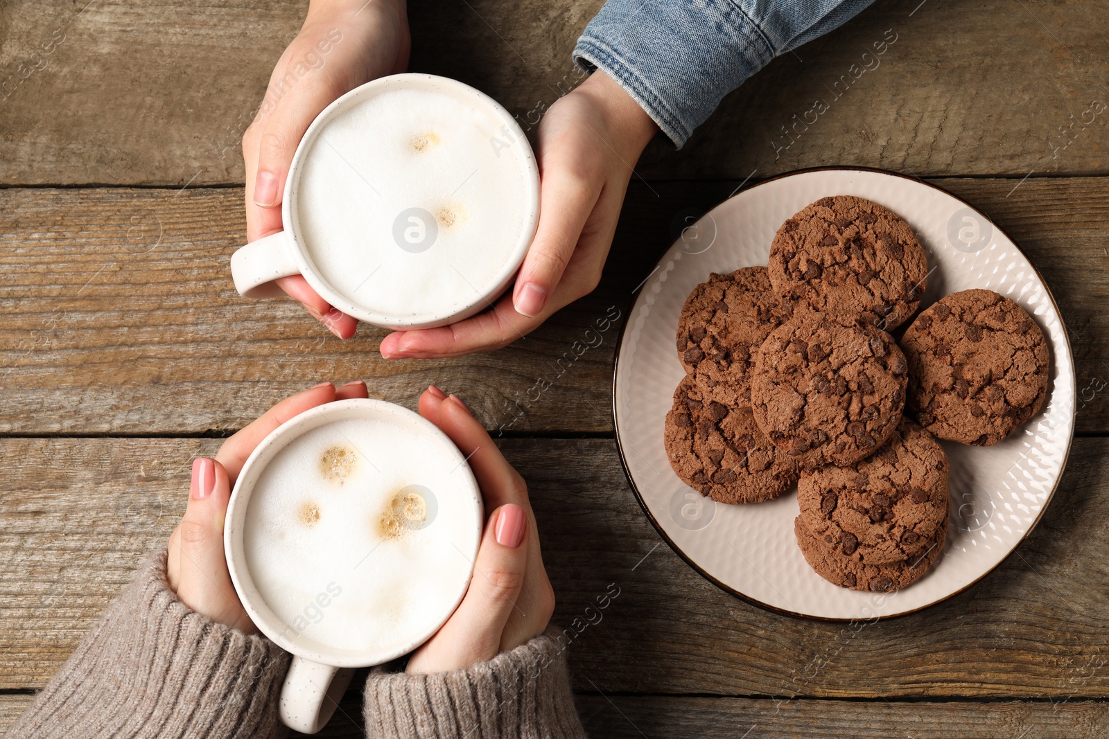 Photo of Women having coffee break at wooden table, top view