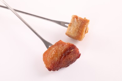 Fondue forks with pieces of fried meat isolated on white