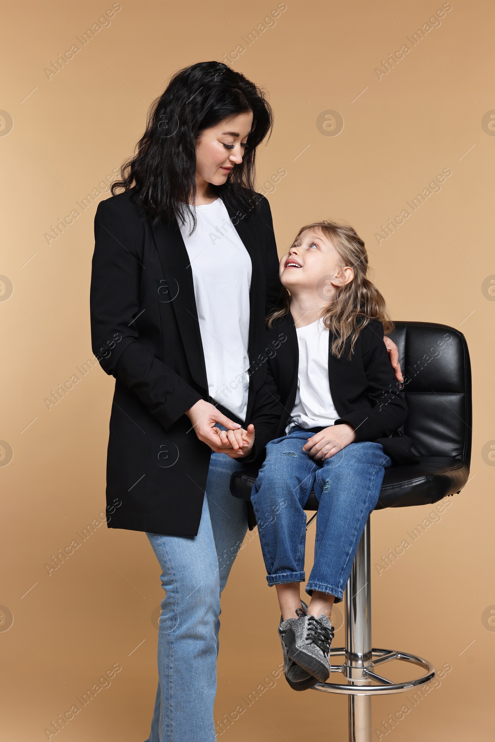 Photo of Beautiful mother with little daughter on beige background