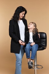 Photo of Beautiful mother with little daughter on beige background