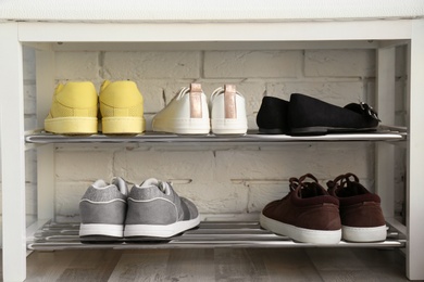 Photo of Collection of stylish shoes on rack storage near white brick wall