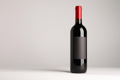 Photo of Bottle of tasty red wine on white background, space for text