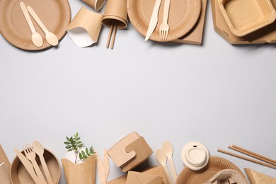 Photo of Eco friendly food packaging. Paper containers, tableware and twigs on light grey background, flat lay. Space for text