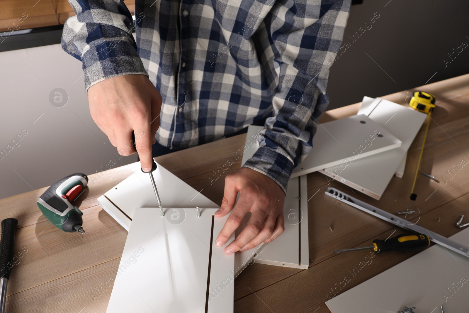 Photo of Man assembling furniture at table indoors, closeup