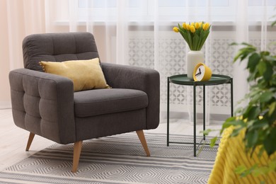 Photo of Spring atmosphere. Stylish living room interior with comfortable furniture and bouquet of beautiful yellow tulips