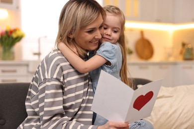 Little daughter congratulating her mom with greeting card at home. Happy Mother's Day