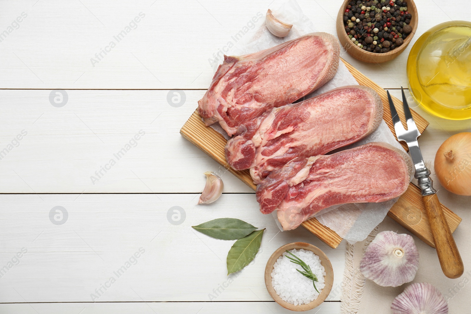 Photo of Raw beef tongue pieces and spices on white wooden table, flat lay. Space for text