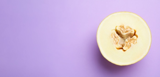 Half of ripe tasty melon on violet background, top view. Space for text