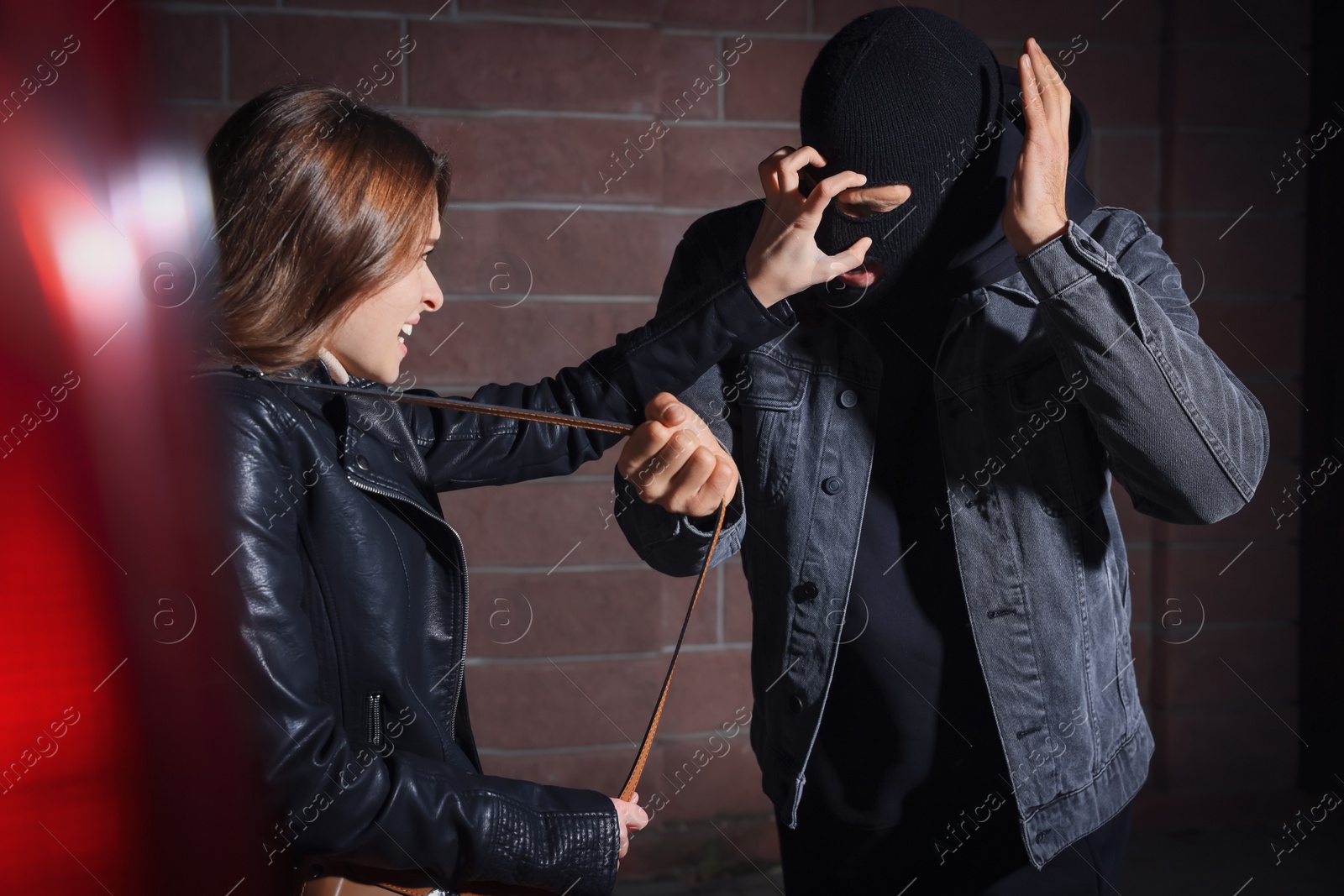 Photo of Woman fighting with thief while he trying to steal her bag outdoors at night. Self defense concept