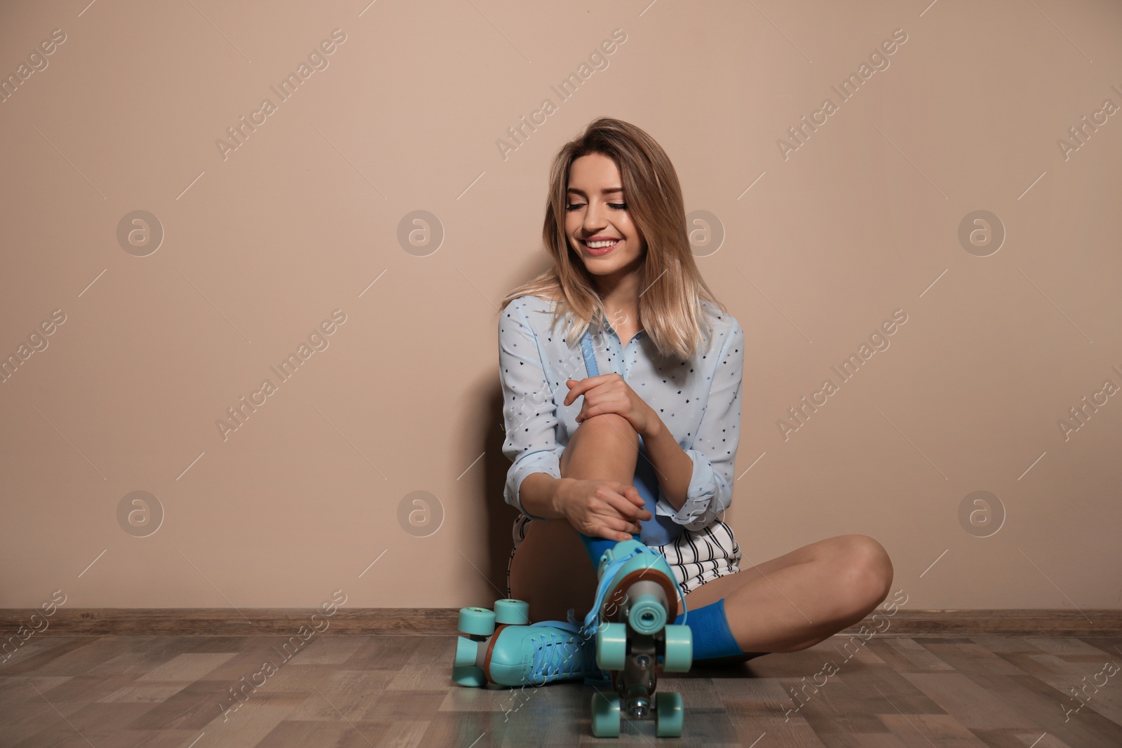 Photo of Young woman with retro roller skates against color wall. Space for text