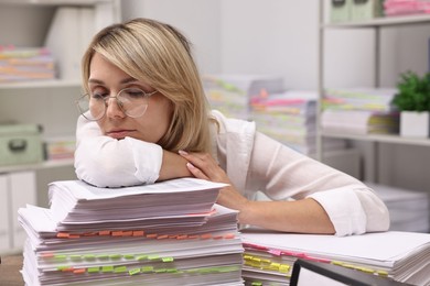 Photo of Overwhelmed woman at table with documents in office