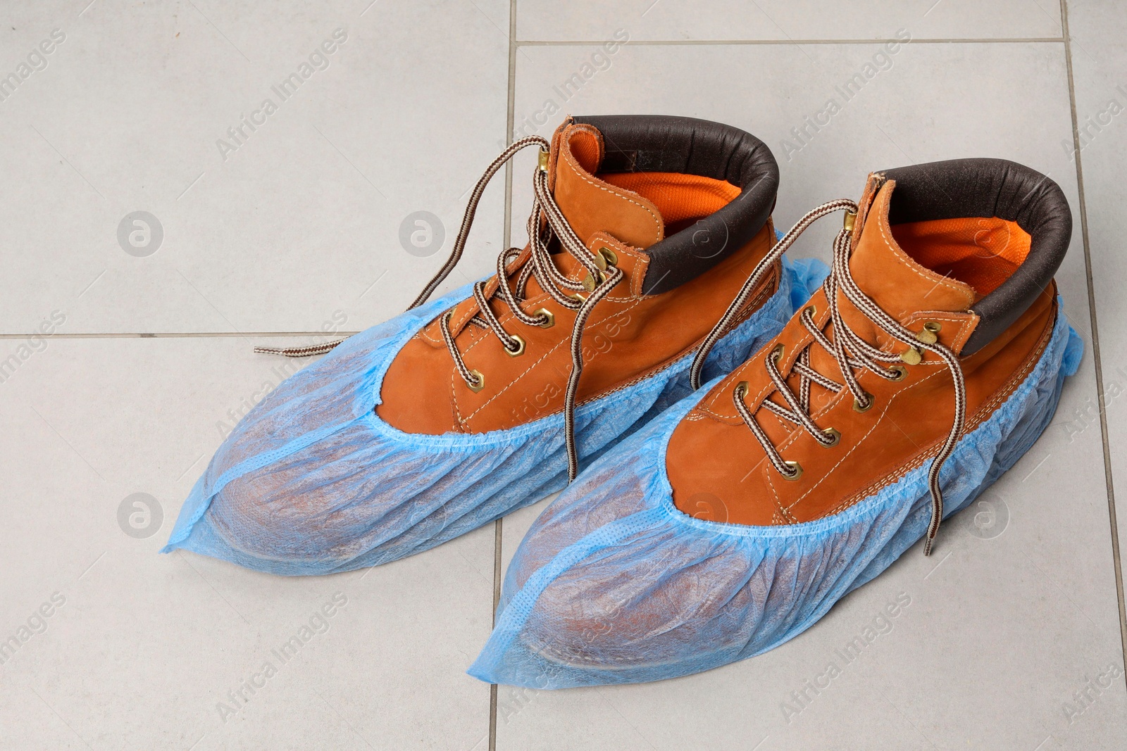 Photo of Men`s boots in blue shoe covers on light floor