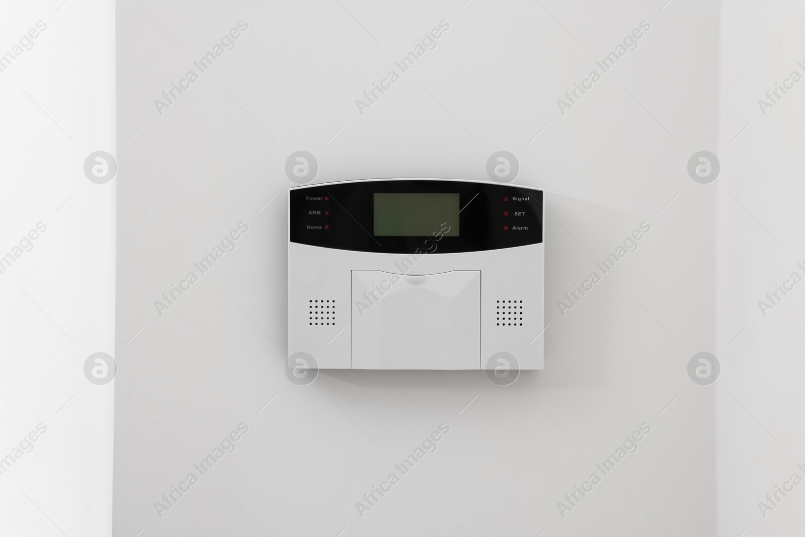 Photo of Home security alarm system on white wall indoors