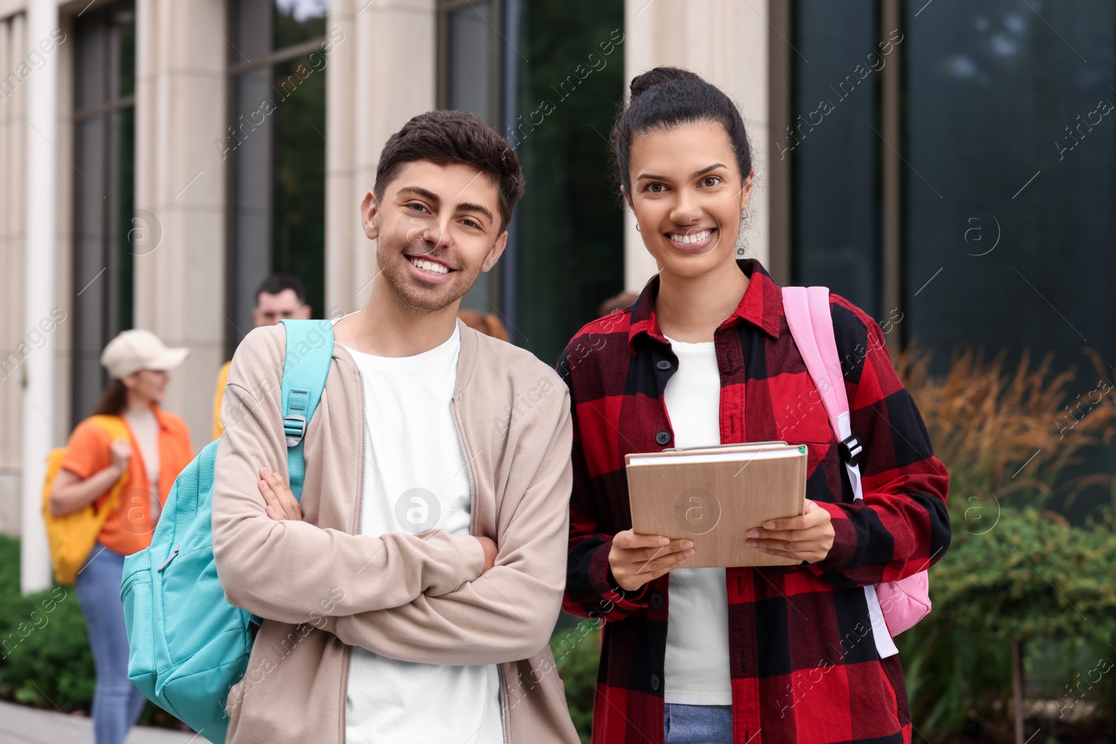 Photo of Portrait of happy young students with backpacks outdoors