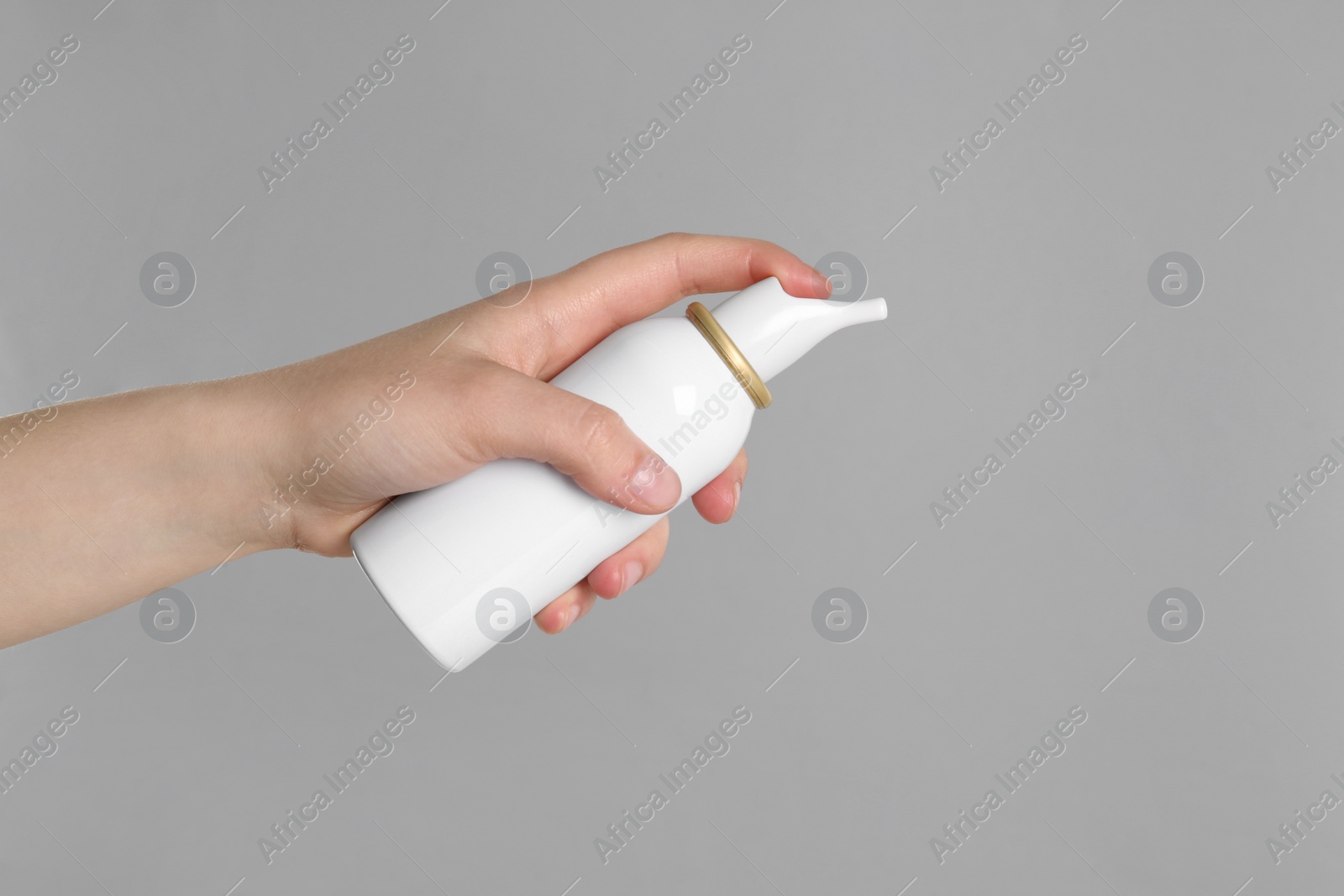 Photo of Woman holding nasal spray on grey background, closeup