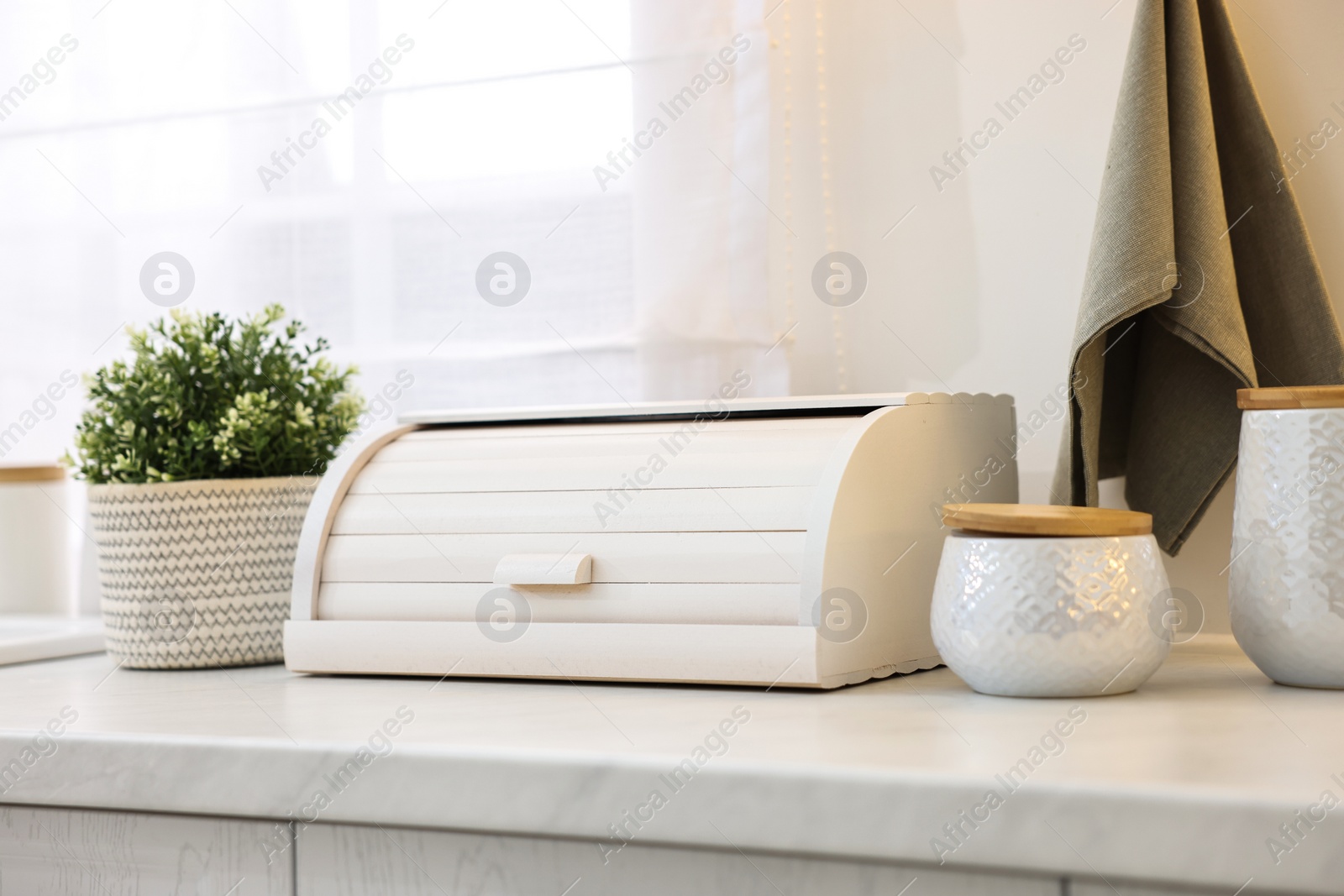 Photo of Wooden bread box and decorative elements on white countertop in kitchen