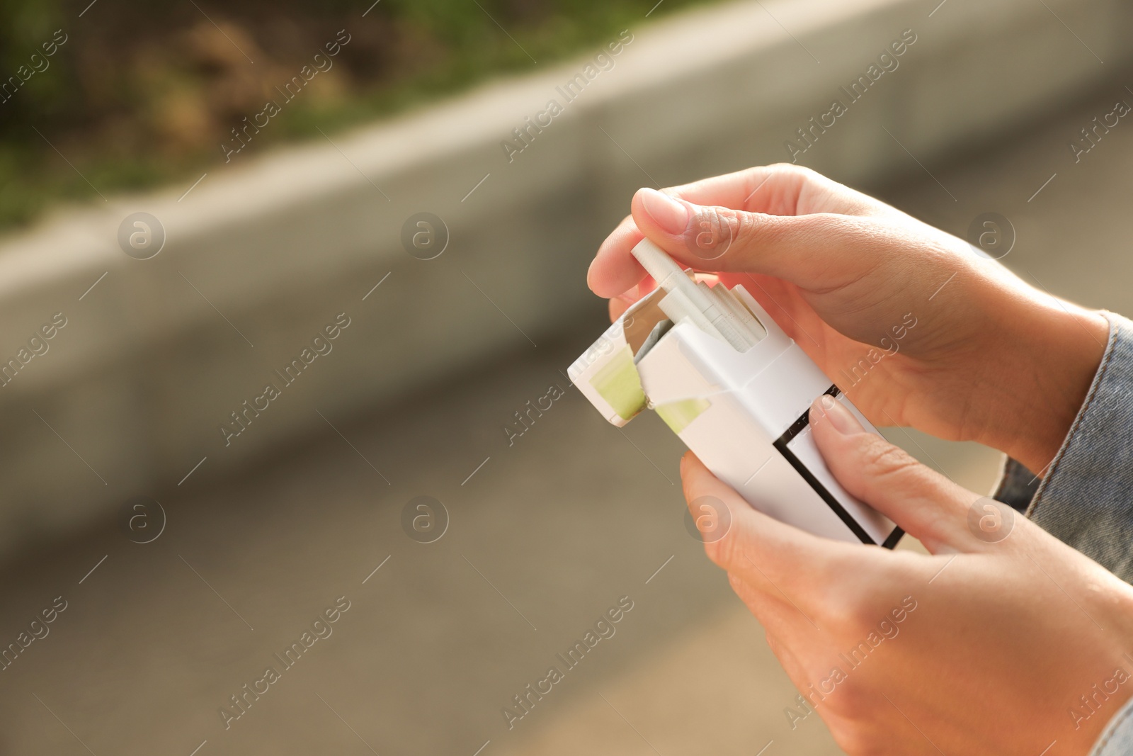 Photo of Woman taking cigarette out of pack outdoors, closeup. Space for text