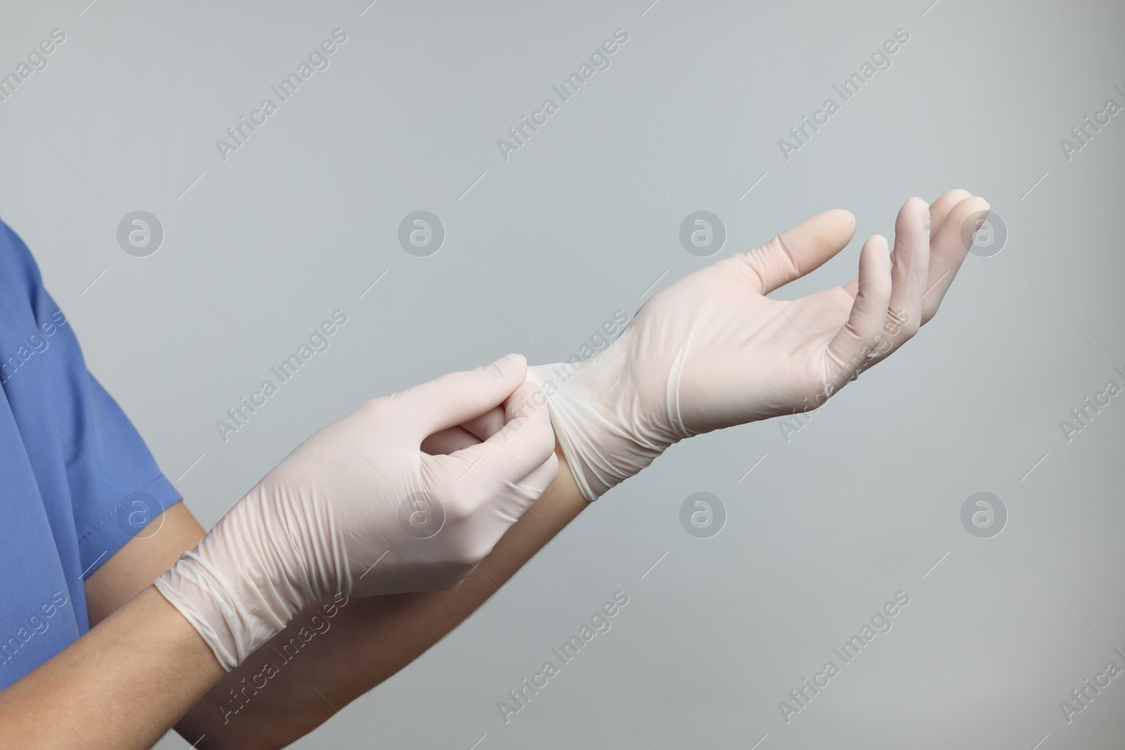 Photo of Doctor wearing white medical gloves on grey background, closeup