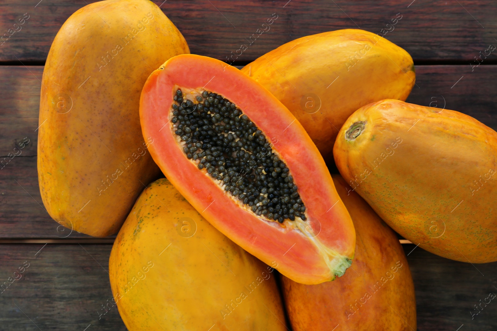 Photo of Fresh ripe cut and whole papaya fruits on wooden table, flat lay