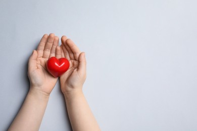 Photo of Child holding red heart on light grey background, top view. Space for text