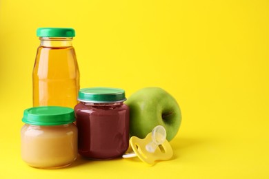 Photo of Healthy baby food, juice, apple and pacifier on yellow background, space for text