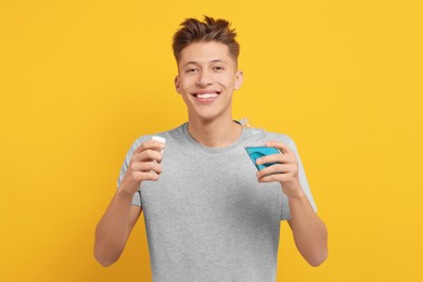 Photo of Young man with mouthwash on yellow background