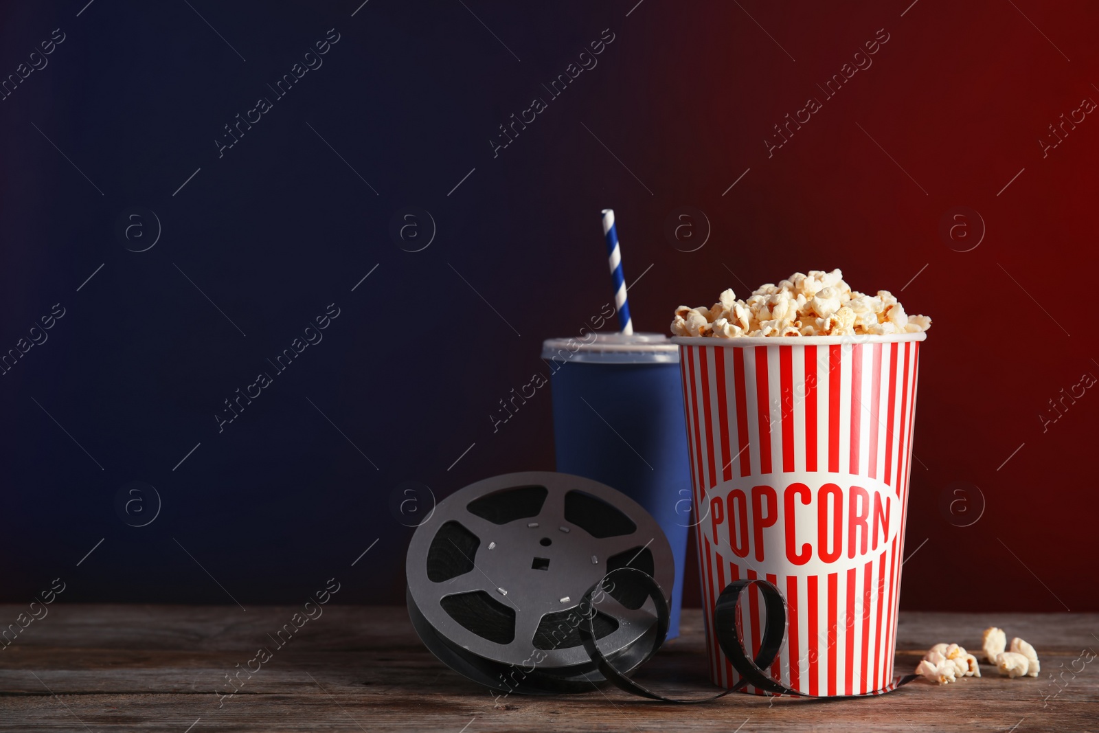 Photo of Composition with popcorn and cinema reel on table against color background. Space for text