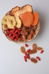 Photo of Wicker basket with different dried fruits on white background, top view