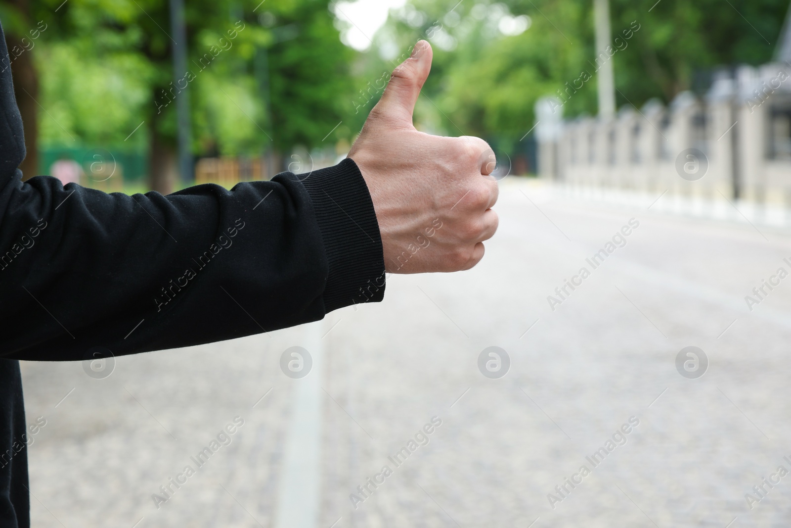 Photo of Man catching car on city street, closeup. Hitchhiking trip