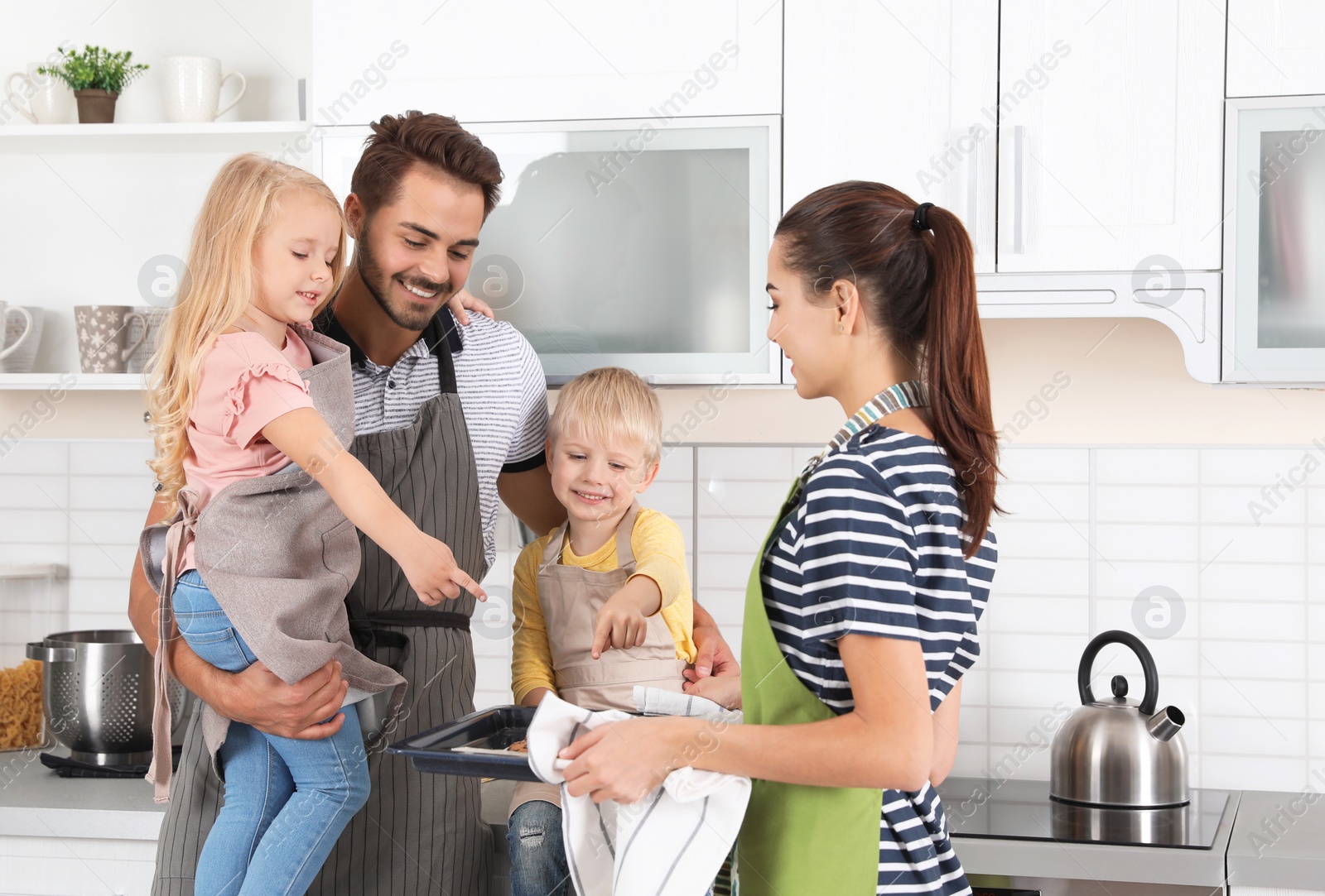 Photo of Young woman treating her family with homemade oven baked pastry in kitchen