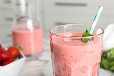 Photo of Tasty strawberry smoothie with mint in glass on table, closeup