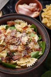 Tasty pasta with bacon and basil on table, closeup