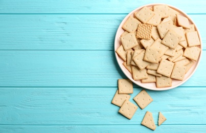 Photo of Delicious crispy crackers on turquoise wooden table, flat lay. Space for text