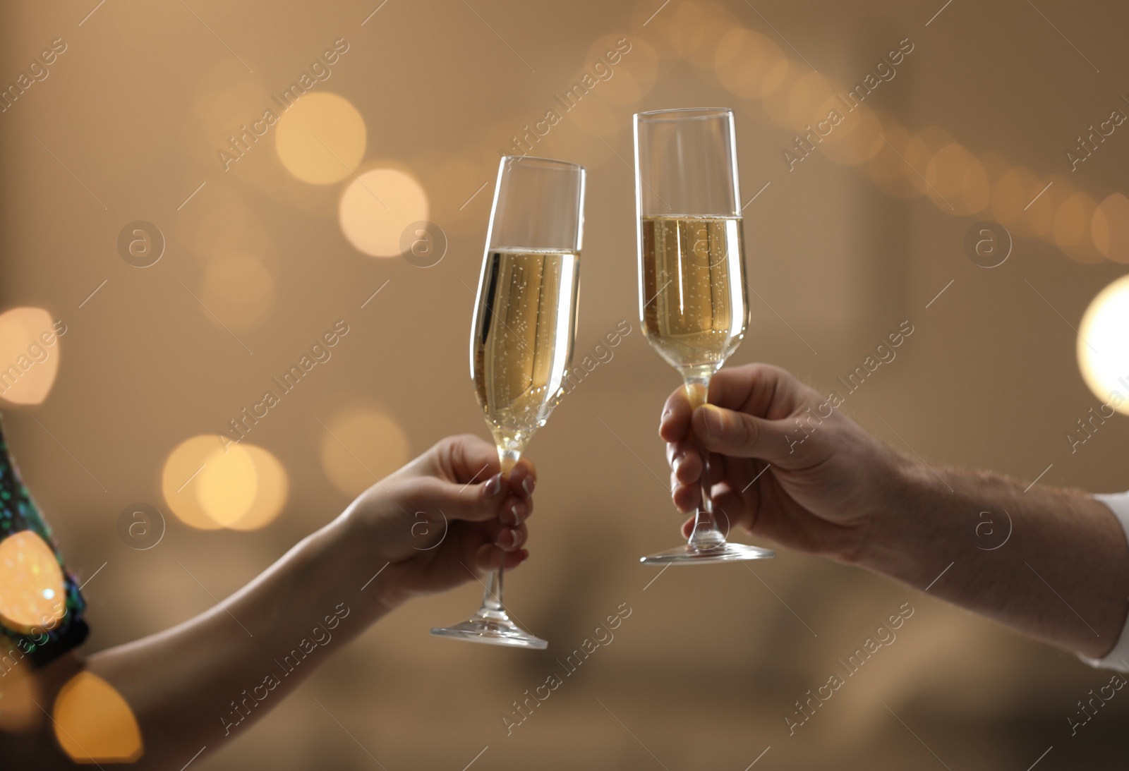 Photo of People clinking glasses of champagne against blurred background, closeup. Bokeh effect