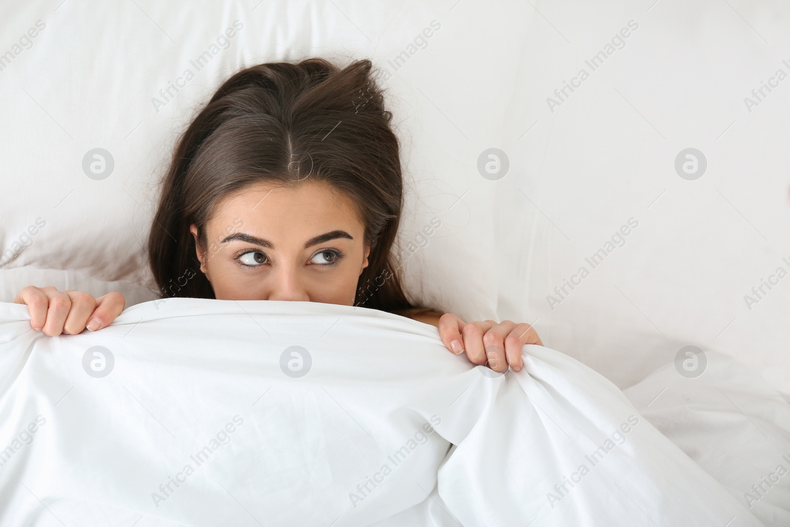 Photo of Young woman lying under blanket, top view. Bedtime