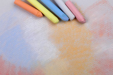 Photo of Colorful pastel chalks on abstract drawing, flat lay. Space for text