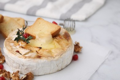 Tasty baked camembert with crouton, thyme, walnuts and pomegranate seeds on white marble table, closeup. Space for text