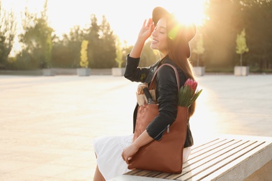 Photo of Young woman with leather shopper bag sitting on bench