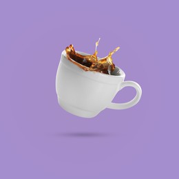 Image of White cup of coffee levitating on violet background