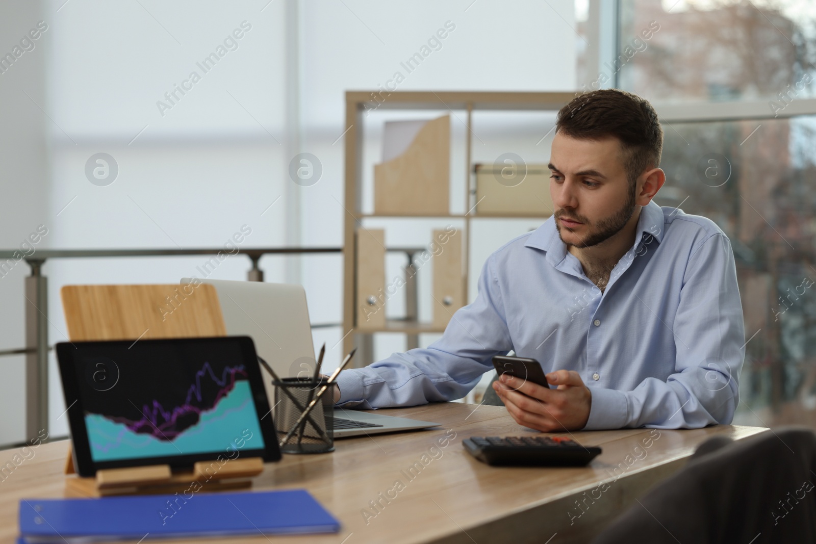 Photo of Forex trader with smartphone working in office