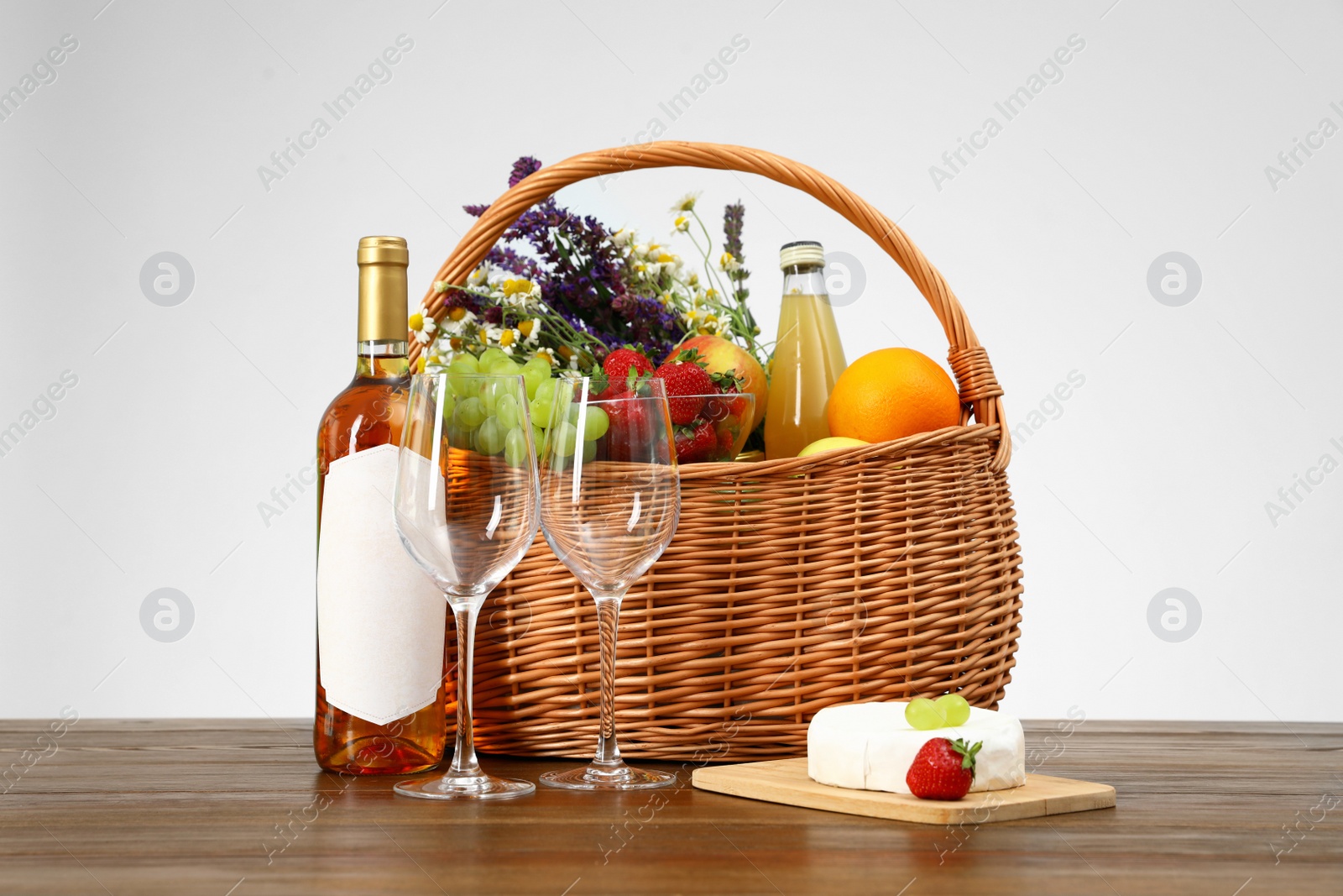 Photo of Picnic basket with wine and products on wooden table against white background